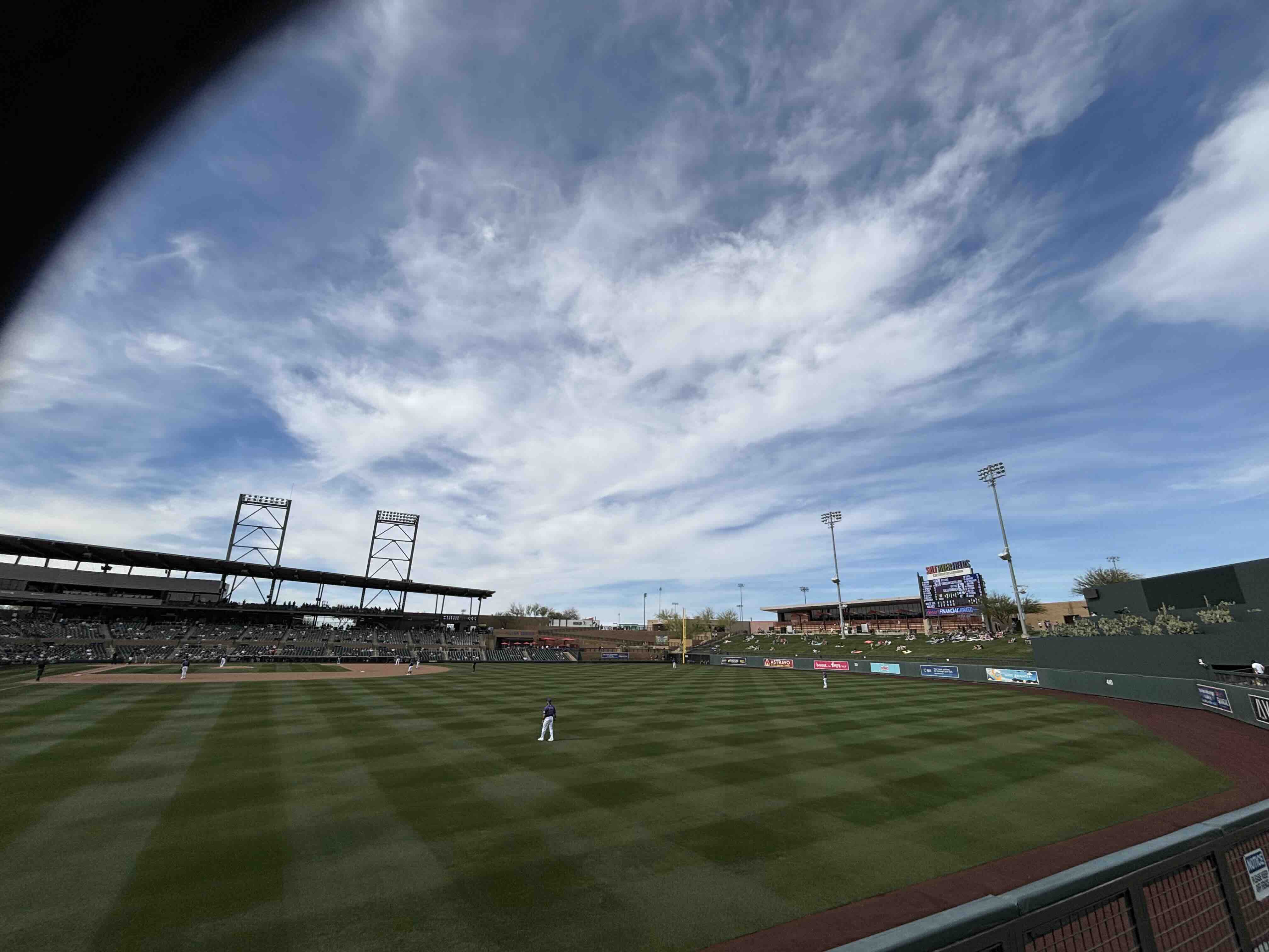 Wide view of Salt River Fields from the left-field lawn with the infield in the distance and fans seated along the grass.